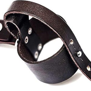 May include: A dark brown leather bracelet with a silver snap closure and silver rivets. The bracelet is curved and appears to be adjustable. The leather has a textured appearance.