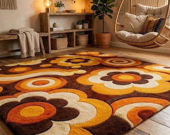 May include: A rectangular area rug featuring a repeating pattern of large, stylized flowers and concentric circles in shades of dark brown, burnt orange, mustard yellow, and cream. The rug has a thick, textured pile and covers a wooden floor.