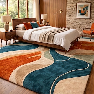 May include: A rectangular area rug featuring a large-scale abstract pattern with flowing, organic shapes in deep teal, burnt orange, and beige. The rug has a plush, textured pile and covers a significant portion of the dark wood floor in the bedroom.