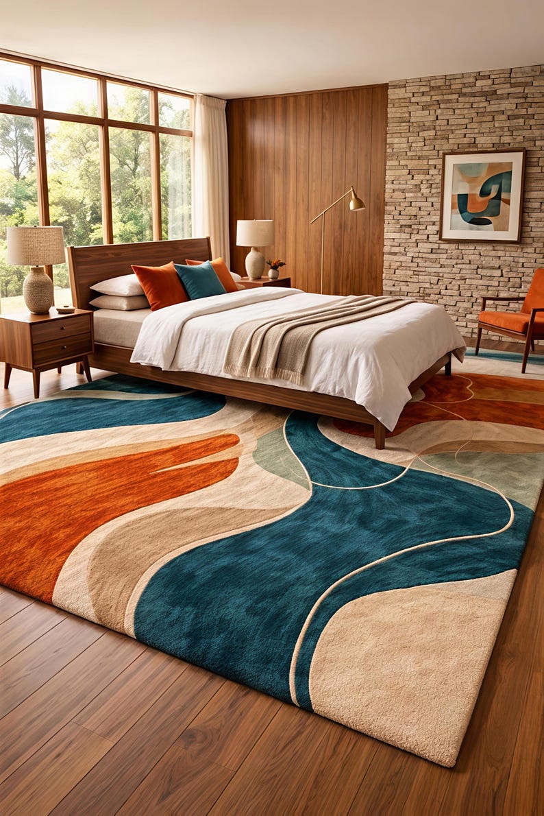 May include: A rectangular area rug featuring a large-scale abstract pattern with flowing, organic shapes in deep teal, burnt orange, and beige. The rug has a plush, textured pile and covers a significant portion of the dark wood floor in the bedroom.