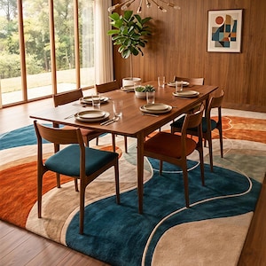 May include: A rectangular area rug featuring a large-scale abstract pattern of wavy, overlapping shapes in deep teal, burnt orange, and beige. The rug is placed under a wooden dining table with six chairs and a sputnik-style chandelier above.