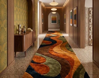 May include: A hallway with a colorful, patterned rug in shades of orange, brown, green, and blue. The walls are wood-paneled with arched doorways and artwork. Overhead, there are several pendant lights.