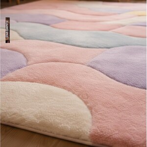 May include: A plush, pastel-colored area rug with a unique, flowing design. The rug features soft, rounded shapes in shades of pink, lavender, gray, and cream. The texture appears fluffy and inviting, suggesting a comfortable and stylish floor covering.