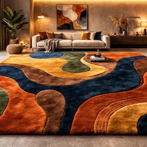 Può includere: Un grande tappeto astratto con un design fluido nei toni dell'arancione, blu, marrone, verde e giallo. Il tappeto si trova in un soggiorno con un divano, opere d'arte e piante. Il design del tappeto assomiglia a un paesaggio.