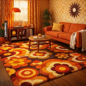 May include: A rectangular area rug featuring a repeating floral pattern in shades of orange, yellow, brown, and cream. The rug has a thick, textured pile and covers a wooden floor, displaying large stylized flower motifs and circular shapes.