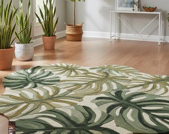 May include: A green and white area rug with a leaf pattern. The rug is shaped like a large leaf and is placed on a hardwood floor. The rug has various shades of green and white.