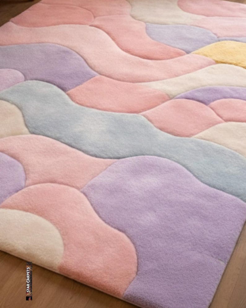 May include: A pastel-colored area rug with an abstract design. The rug features flowing, organic shapes in shades of pink, lavender, blue, and cream. The soft, plush texture and muted color palette create a calming and inviting aesthetic. The rug is a decorative floor covering.