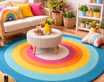 May include: A colorful outdoor living space featuring a round rug with concentric circles in shades of blue, yellow, orange, and pink. The space includes a white wicker sofa with rainbow and solid-colored pillows, potted plants, and a small white table.