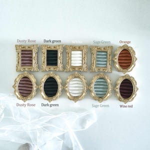 May include: Ten ornate gold-toned frames with velvet ring inserts in various colors including dusty rose, dark green, white, sage green, orange, and wine red. The top row features rectangular frames, while the bottom row contains oval frames.