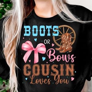 May include: Black sweatshirt with the text "BOOTS OR BOWS COUSIN Loves You". The design includes a pink bow, cowboy boots, and a wagon wheel. The text is in blue, pink, and brown.