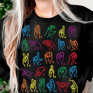 May include: Black sweatshirt with a vibrant graphic of hand gestures representing the British Sign Language alphabet. Each hand sign is outlined in a different bright colour, with corresponding letters.