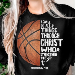 Puede incluir: Sudadera negra con un gráfico de baloncesto y el texto blanco "I CAN DO ALL THINGS THROUGH CHRIST WHO STRENGTHENS ME". El texto "PHILIPPIANS 4:13" está impreso en la parte inferior.