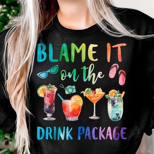May include: Black sweatshirt with the text "BLAME IT on the DRINK PACKAGE" in rainbow colors. The design includes sunglasses, a camera, flip-flops, and watercolor illustrations of four different cocktails.