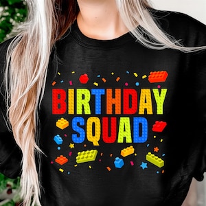 May include: Black sweatshirt featuring the text "BIRTHDAY SQUAD" in a colourful block design. The design includes various block shapes and confetti. A fun top for a birthday party.