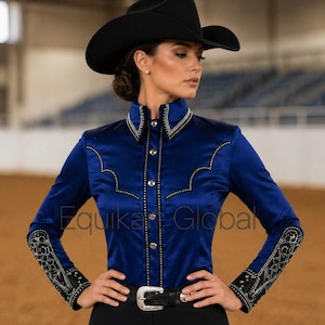 Könnte beinhalten: Eine marineblaue Western-Show-Bluse mit silbernen und goldenen Verzierungen, schwarze Hose und ein schwarzer Cowboyhut. Die Bluse hat lange Ärmel mit detaillierten Manschetten und einen hohen Kragen. Der Gürtel hat eine silberne Schnalle. Der Text "Equika Global" ist sichtbar.