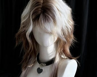 May include: A layered wig with a mix of brown, blonde, and white strands. The wig features a fringe and wavy texture. A black choker with a heart pendant is worn on a mannequin head against a dark backdrop.