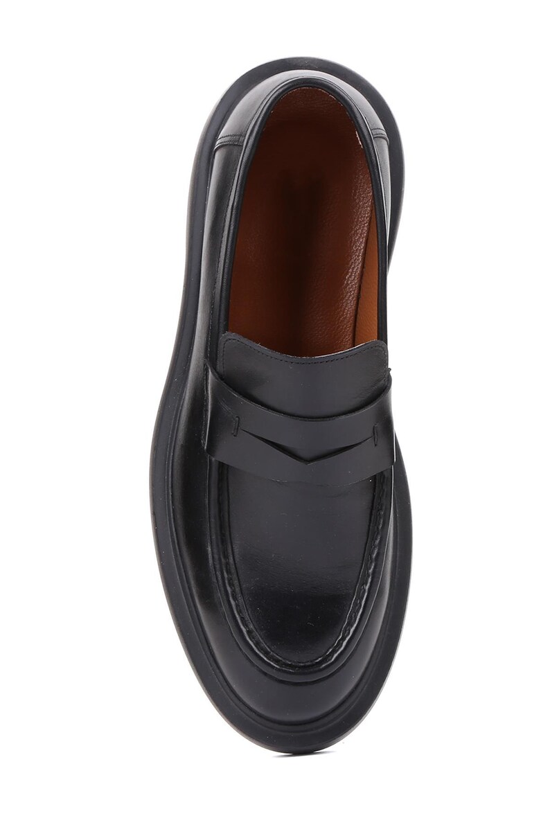 Puede incluir: Mocas&iacute;n de cuero negro con punta redondeada y suela gruesa. El zapato presenta una correa en el empeine con un dise&ntilde;o decorativo. El interior es de color marr&oacute;n claro. Un estilo de calzado cl&aacute;sico.