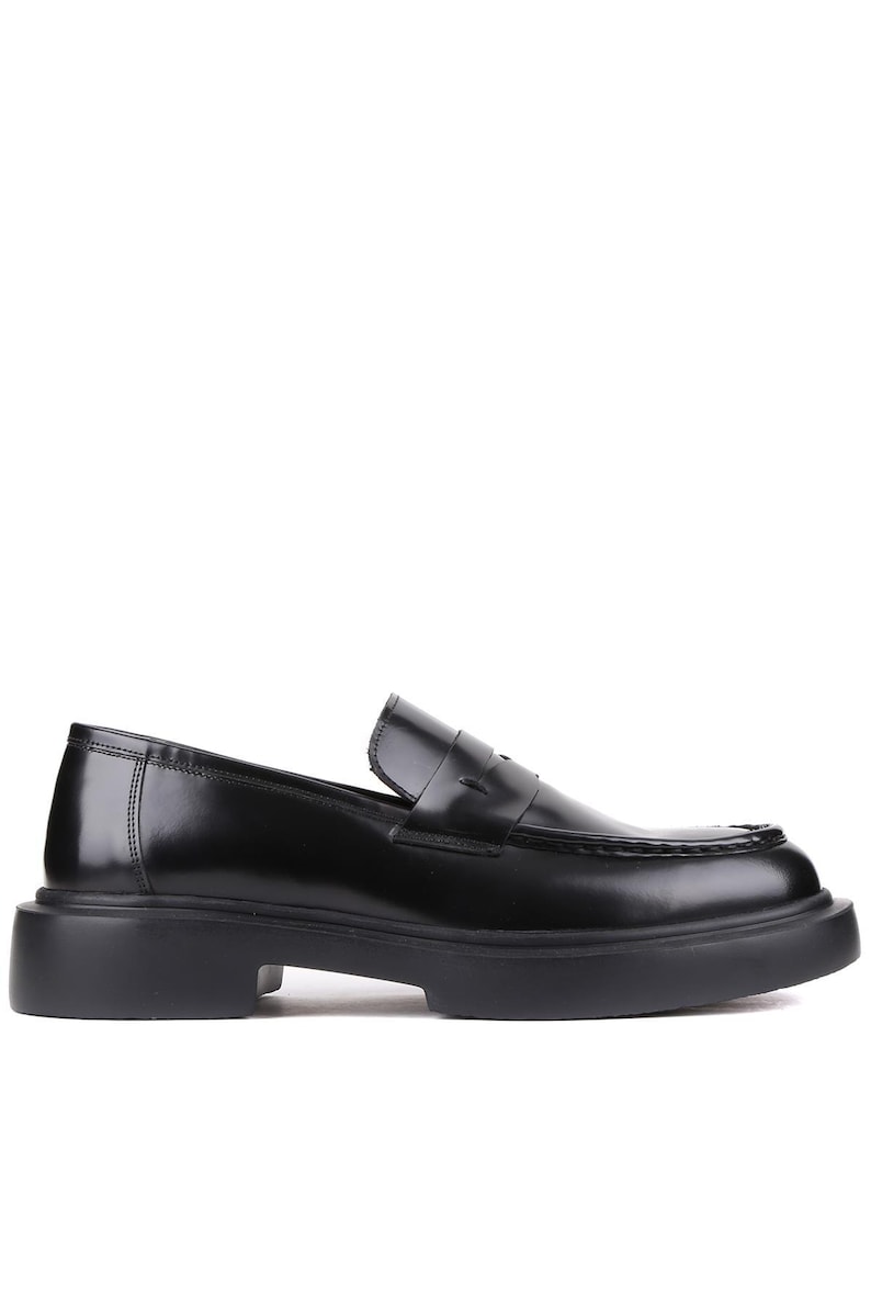 Puede incluir: Mocas&iacute;n de cuero negro con suela gruesa. El zapato presenta un dise&ntilde;o cl&aacute;sico de mocas&iacute;n con borlas, con punta redonda y tac&oacute;n bajo. El acabado brillante a&ntilde;ade un toque de sofisticaci&oacute;n a este calzado.