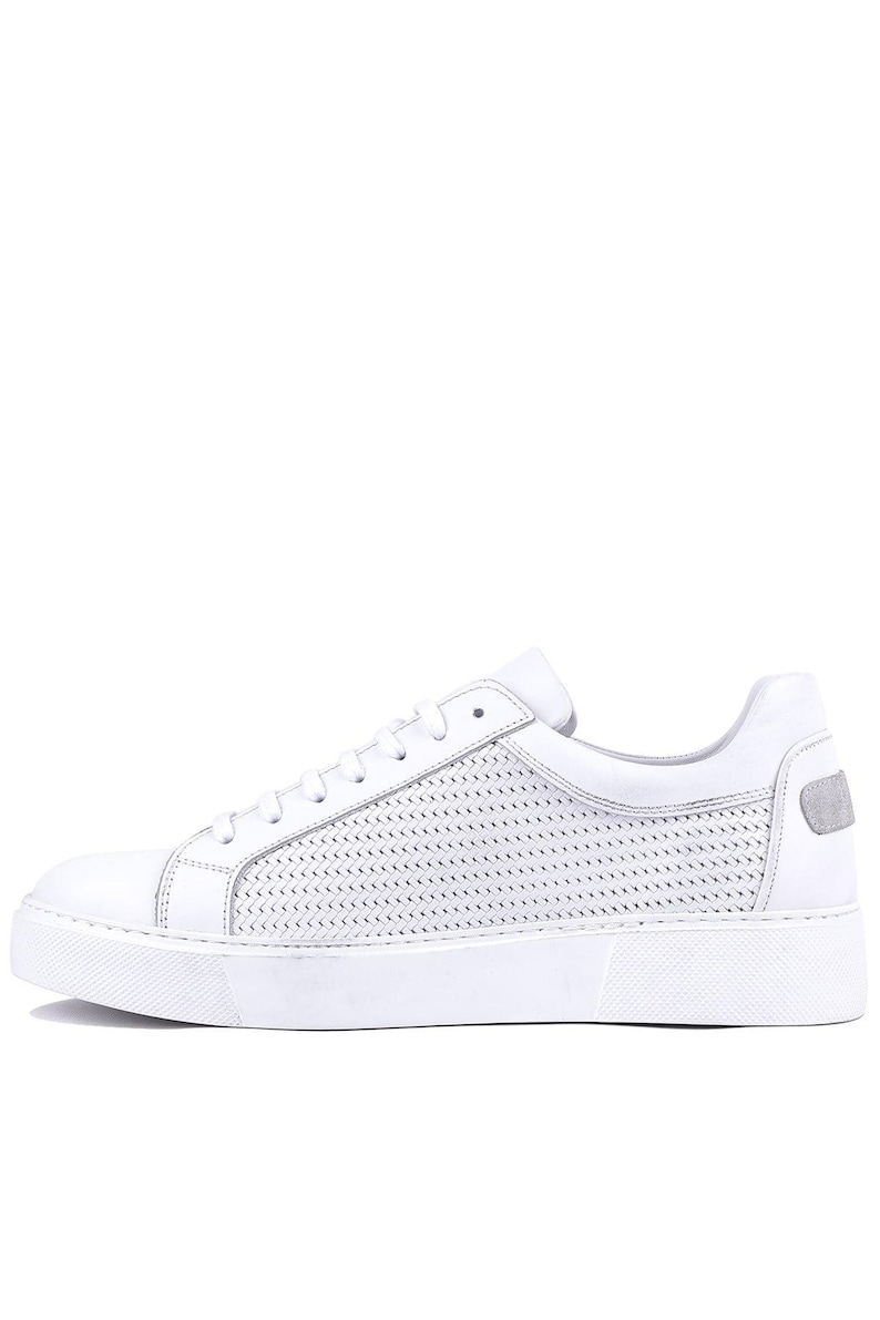 May include: White leather sneakers with a low-top design. The shoe features a perforated pattern on the side and a solid white sole. A small, gray accent is on the heel.