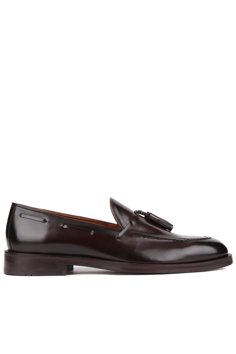 Op de afbeelding: Een enkele, donkerbruine leren loafer met een kwastje. De schoen heeft een gepolijste afwerking, een ronde neus en een lage hak. Het ontwerp is klassiek en elegant, geschikt voor formele of semi-formele gelegenheden.