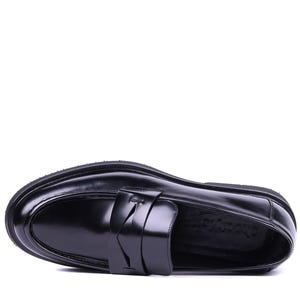 May include: A black leather loafer with a rounded toe and a thick sole. The shoe features a strap detail across the top. The shoe is approximately 11 inches long.