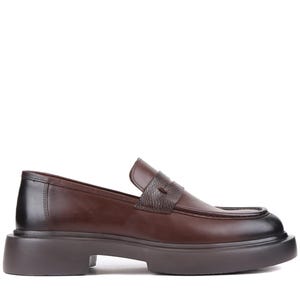 Puede incluir: Mocas&iacute;n de cuero marr&oacute;n con suela gruesa. El zapato presenta una puntera redondeada, una correa texturizada en el empeine y una suela marr&oacute;n oscuro. El tac&oacute;n mide aproximadamente 3,8 cm de alto.