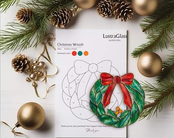 Op de afbeelding: Een kerstkransontwerp met een rode strik en groene bladeren, naast een afgedrukte sjabloon. De sjabloon is gelabeld "Christmas Wreath" en is 20 cm bij 20 cm. De afbeelding is omgeven door kerstversieringen en dennennaalden.