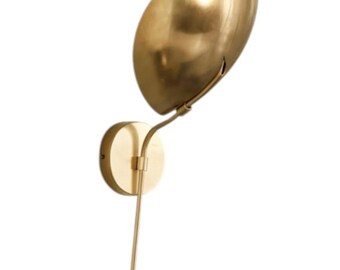 May include: A modern wall sconce with a gold finish. The fixture features a rounded base, a slender arm, and a leaf-shaped shade. The shade is angled upwards, and the overall design is minimalist and elegant.