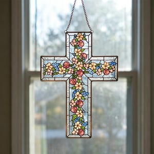 Op de afbeelding: Gebrandschilderd glazen kruis met een bloemenontwerp. Het kruis is gemaakt van helder en lichtblauw glas, met een koperkleurig metalen frame. De bloemen zijn roze, geel en blauw. Het hangt aan een ketting.