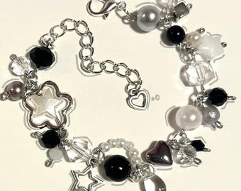 May include: A silver-toned charm bracelet featuring a variety of beads and charms. The bracelet includes black, white, and gray beads, along with star and heart-shaped charms. The bracelet has a lobster clasp closure.