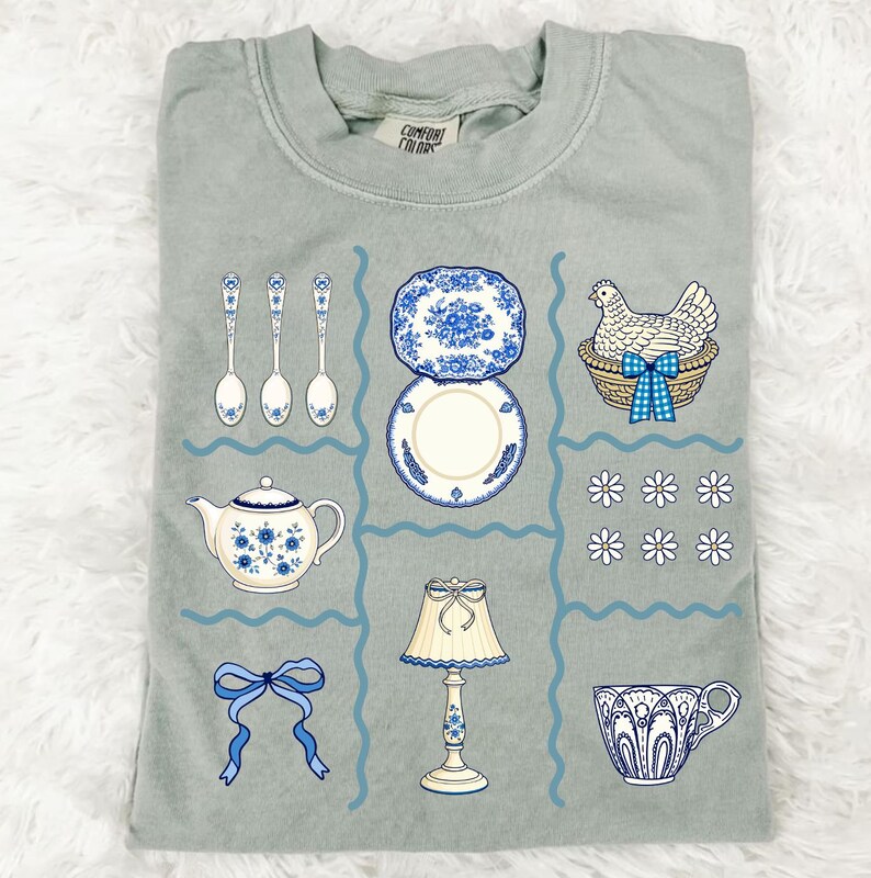 Pode incluir: Camiseta verde s&aacute;lvia com um design de grade com ilustra&ccedil;&otilde;es de uma chaleira, pratos, colheres, uma l&acirc;mpada, uma x&iacute;cara de ch&aacute;, um la&ccedil;o e uma galinha em uma cesta. As ilustra&ccedil;&otilde;es s&atilde;o em azul e branco.