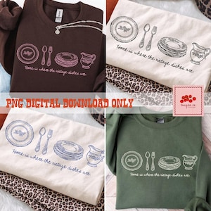 May include: Four sweatshirts in different colors: brown, cream, off-white, and green. Each sweatshirt features a line drawing of a plate, spoon, fork, stack of plates, and a pitcher. The text "Home is where the vintage dishes are" is printed below the drawing.