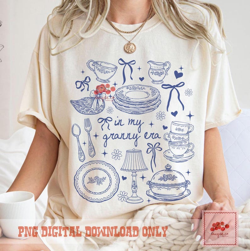 May include: A cream-coloured t-shirt featuring a blue illustration of teacups, plates, and the text "in my + granny era." The design includes bows, flowers, and a lamp. The phrase "PNG DIGITAL DOWNLOAD ONLY" is printed at the bottom.