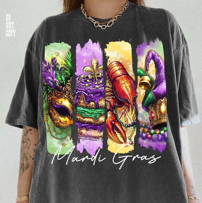May include: Dark gray t-shirt featuring a colorful Mardi Gras design. The graphic includes a mask, cake, crawfish, and jester hat, with the words "Mardi Gras" in white script. The design is printed on a comfortable, casual tee.
