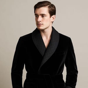 Könnte beinhalten: Ein schwarzer Samt-Bademantel mit gestepptem Schalkragen und passendem Gürtel. Der Bademantel hat ein klassisches Design mit maßgeschneiderter Passform und einer Brusttasche. Der luxuriöse Stoff und die eleganten Details schaffen einen raffinierten Look.