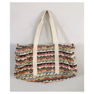May include: A multi-colored geometric patterned duffel bag with white straps.