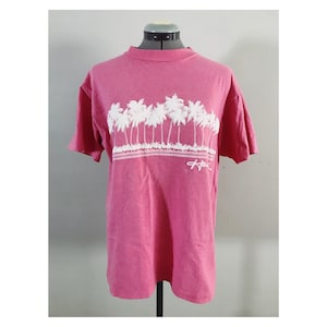 May include: A pink t-shirt with a white graphic of palm trees and the word "Hawaii" on the front.