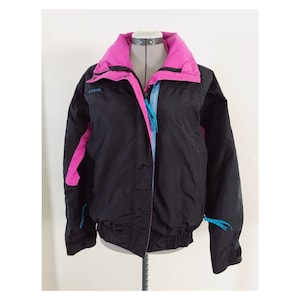 May include: A black, pink, and blue vintage Columbia ski jacket with a zipper closure. The jacket has a drawstring waist and a logo on the left chest.