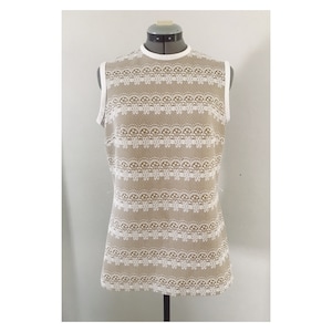 May include: A sleeveless top with a white lace pattern on a beige background.