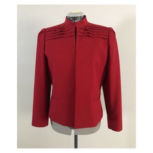 May include: A red blazer with a mandarin collar and pleated detail on the shoulders.