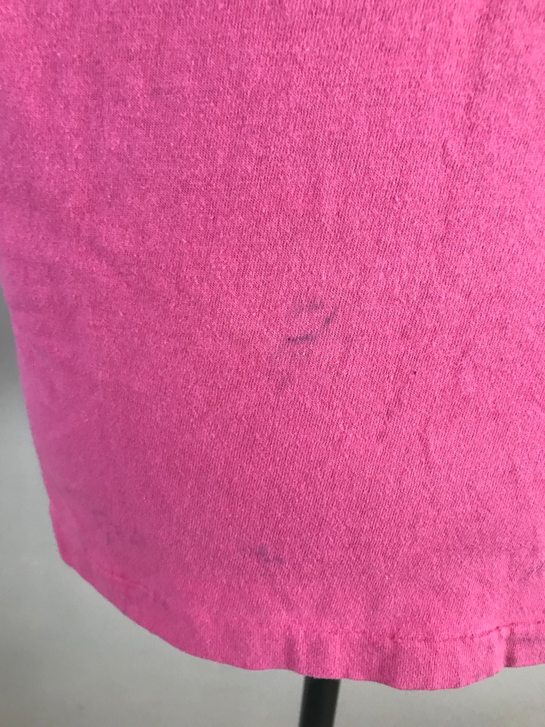 May include: A pink t-shirt with a slight fade in the colour. The shirt is made of a soft, comfortable fabric.