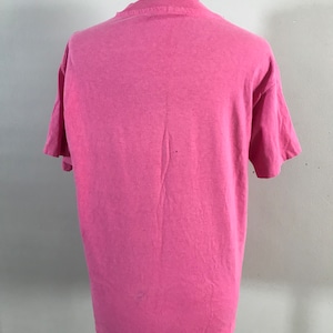 May include: A pink short-sleeved t-shirt on a mannequin. The t-shirt is plain with no visible graphics or text.