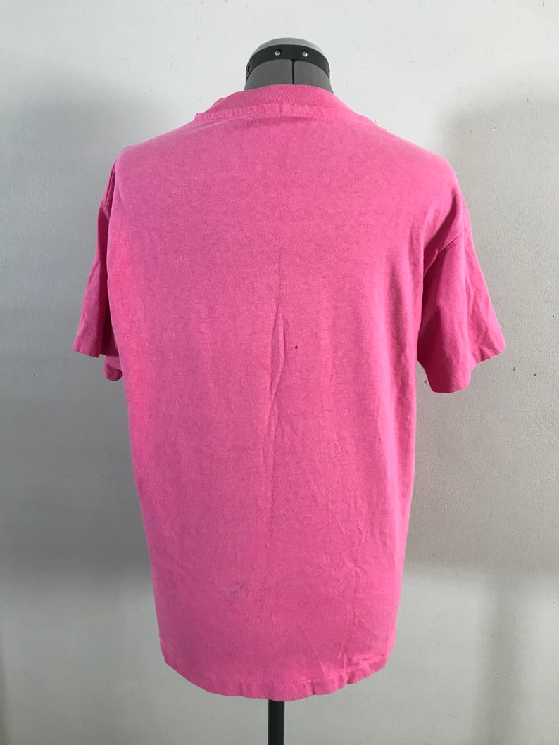 May include: A pink short-sleeved t-shirt on a mannequin. The t-shirt is plain with no visible graphics or text.