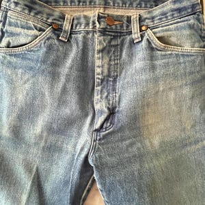Puede incluir: Unos vaqueros de mezclilla azul claro con un dise&ntilde;o cl&aacute;sico de cinco bolsillos, cierre de botones y remaches met&aacute;licos de color cobre en las esquinas de los bolsillos. La tela presenta un lavado desgastado con costuras visibles y cintura.