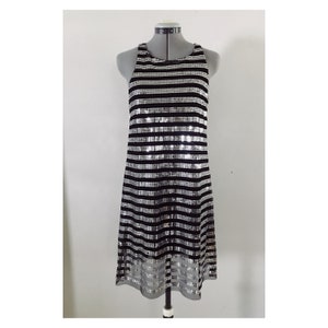 May include: A black and silver striped sleeveless dress with a sequined design. The dress has a loose fit and a slightly flared hem.