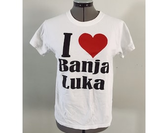 May include: White t-shirt with a black graphic that says "I love Banja Luka" with a red heart.