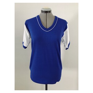 May include: A blue and white short-sleeved t-shirt with a v-neck collar. The sleeves are white with blue trim.