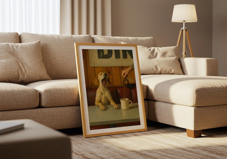 Puede incluir: Una impresi&oacute;n enmarcada que presenta a un perro bostezando en una mesa de restaurante mientras se vierte caf&eacute; en una taza. La impresi&oacute;n tiene un marco de madera clara y est&aacute; apoyada contra un sof&aacute; beige. El letrero del restaurante dice "DIN".