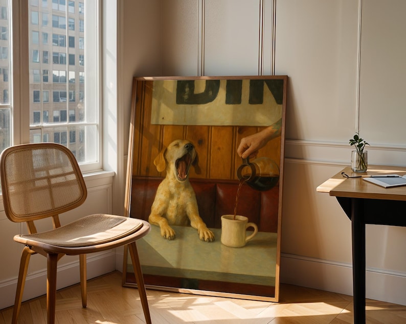 Puede incluir: Una obra de arte enmarcada representa a un perro bostezando en una mesa de restaurante mientras se vierte caf&eacute; en una taza. La obra est&aacute; apoyada contra una pared junto a una ventana y una silla de madera. La escena est&aacute; ba&ntilde;ada por la luz natural.