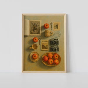 Puede incluir: Impresión artística enmarcada que representa una naturaleza muerta. La imagen incluye un libro, manzanas, tazas, un plato pequeño, una cuchara, dos cámaras y un libro titulado "WILLIAM MORRIS". Paleta de colores cálidos, estética vintage.